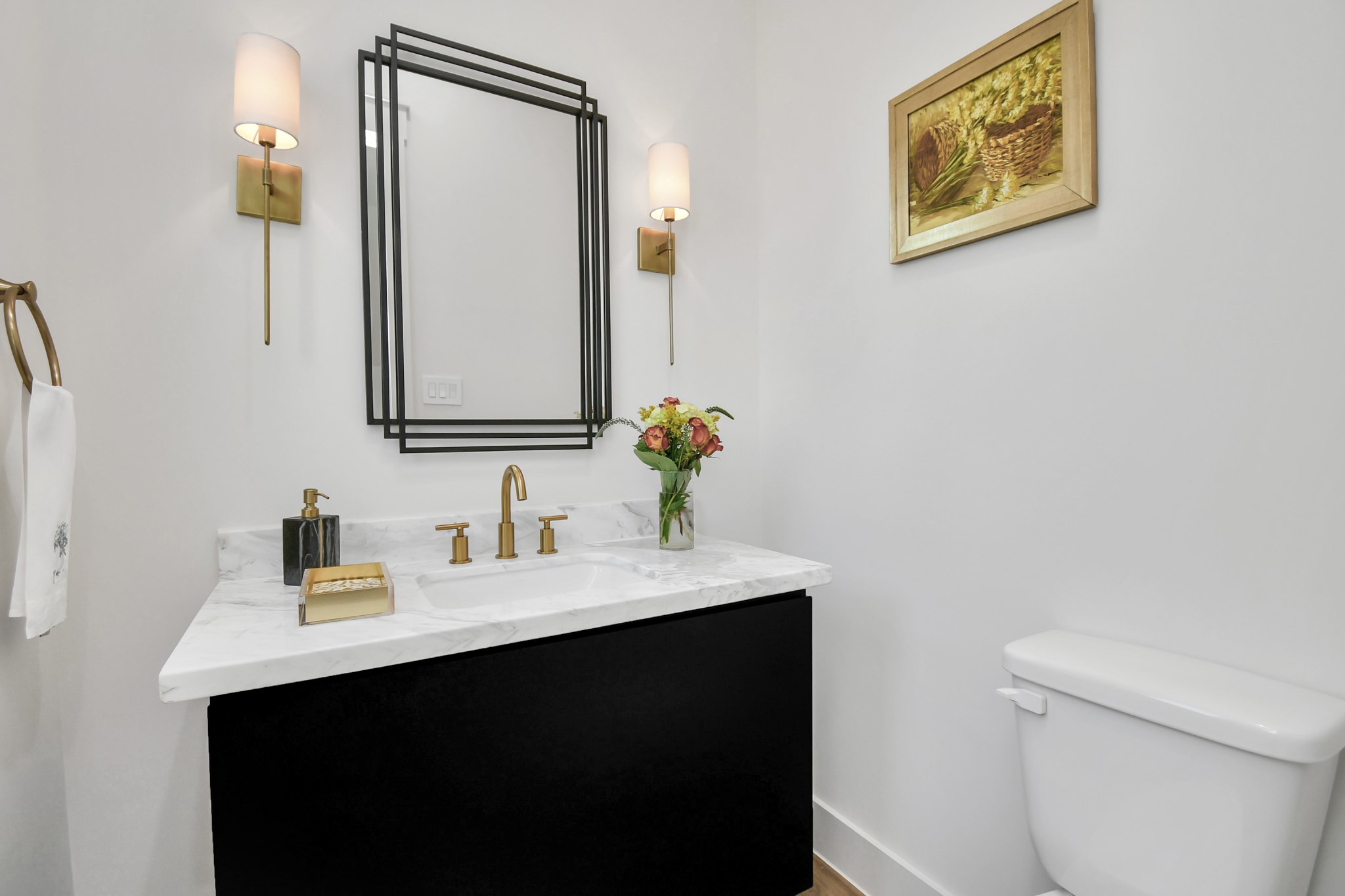 2512 Gray Street Houston, TX 77003 - Photo 8 of 46 This bathroom features a sleek black vanity with a marble countertop, gold fixtures, and a stylish mirror. Elegant wall sconces and tasteful decor enhance its modern aesthetic.
