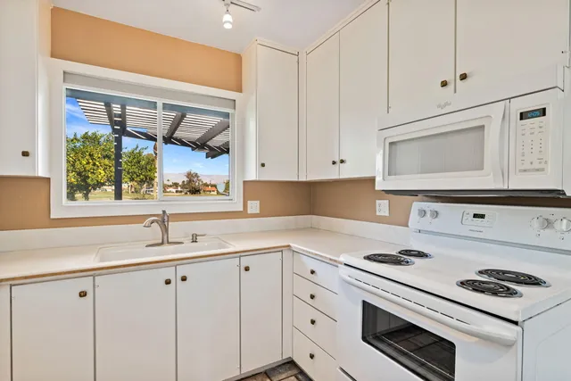 a kitchen with white cabinets and appliances