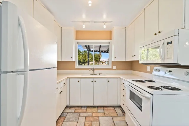 a kitchen with white cabinets and white appliances