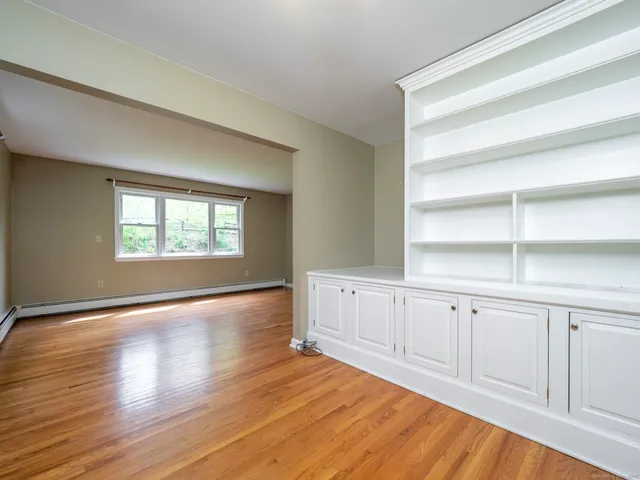 a view of an empty room with a window and wooden floor
