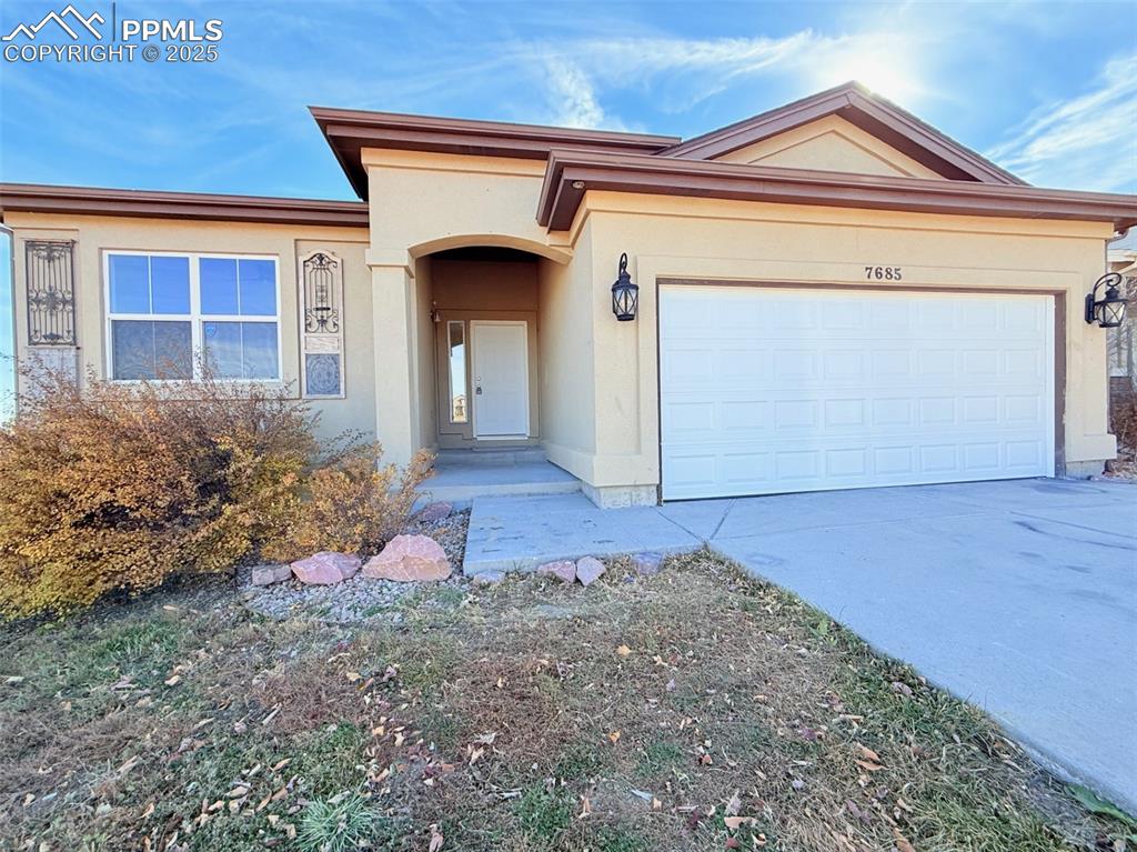 View of front of property featuring stucco siding, concrete driveway, and a garage