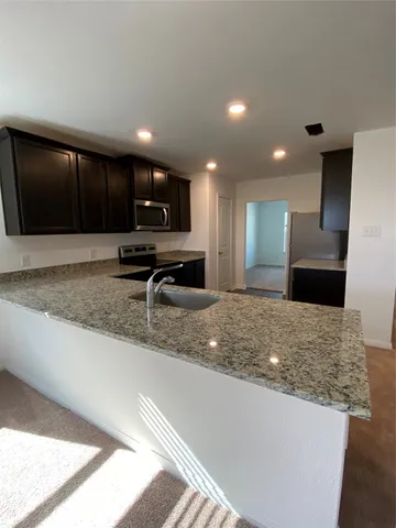 a view of kitchen island a sink wooden floor and a living room