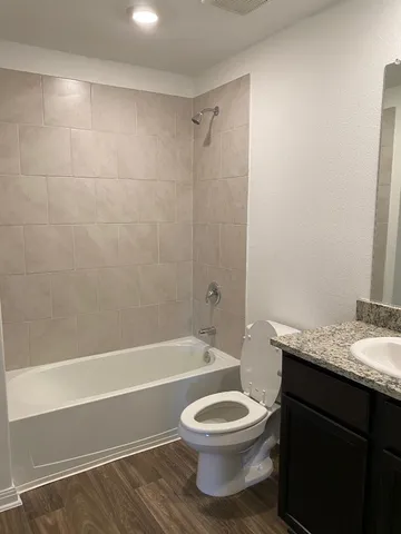 a bathroom with a granite countertop toilet a sink and bathtub