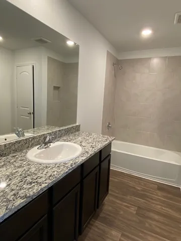 a bathroom with a granite countertop bathtub sink and mirror