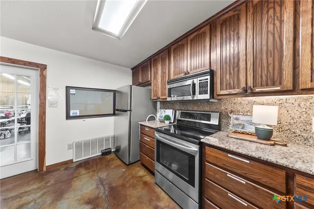 a kitchen with granite countertop wooden cabinets stainless steel appliances and a window