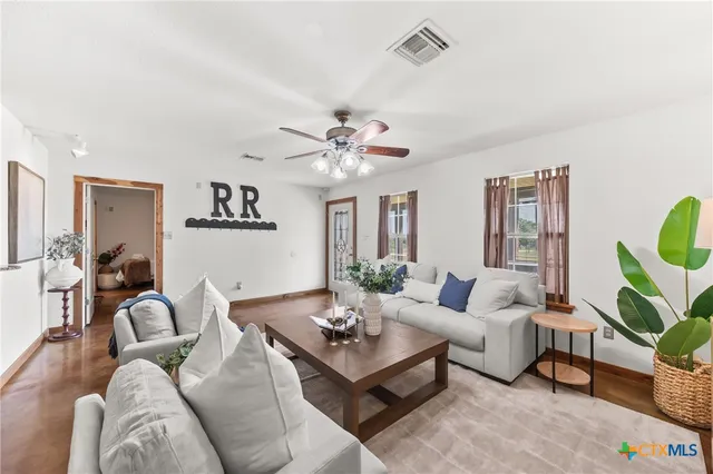 a living room with furniture a chandelier and a potted plant