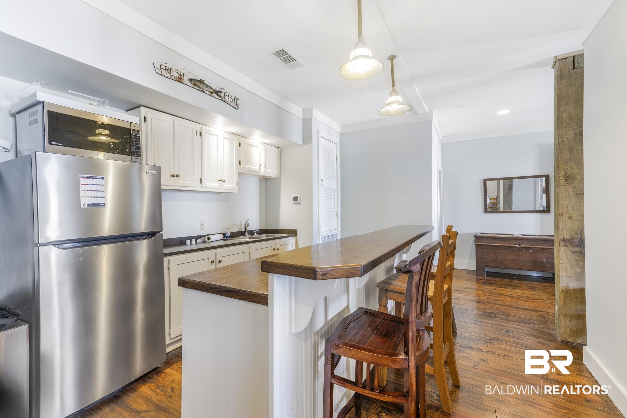 25773 Canal Road Orange Beach, AL 36561 - Photo 27 of 32 Kitchen with appliances with stainless steel finishes, dark wood-style flooring, a breakfast bar area, white cabinets, and pendant lighting