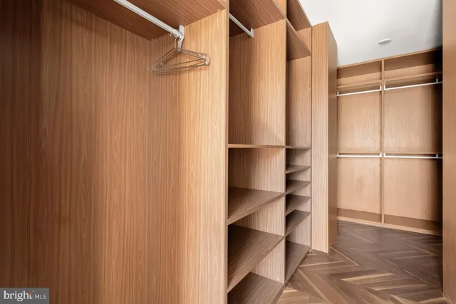 a walk in closet with wooden floor