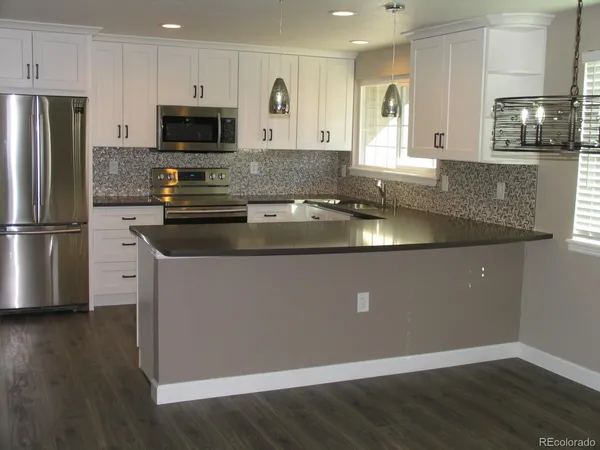 a kitchen with granite countertop a refrigerator and a stove top oven