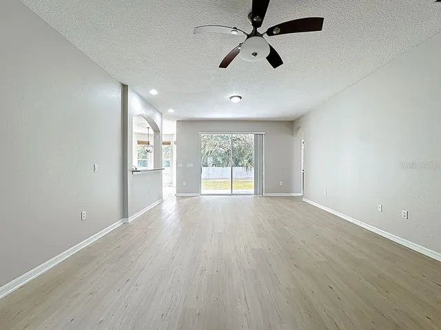 an empty room with windows and chandelier fan