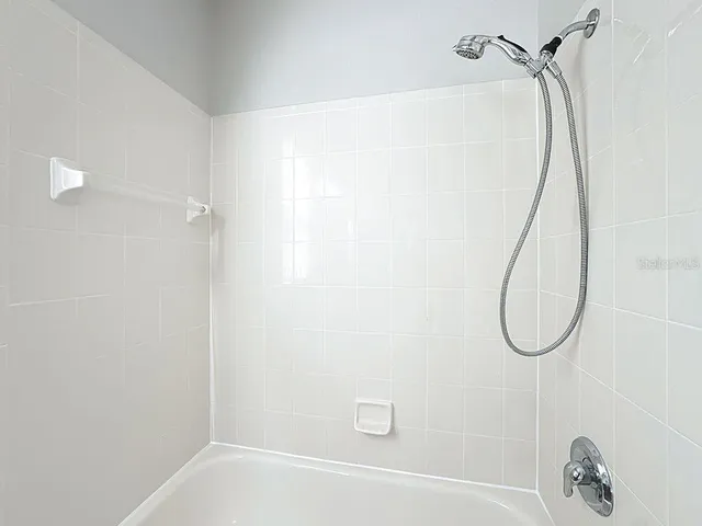 a view of an empty room with chandelier fan
