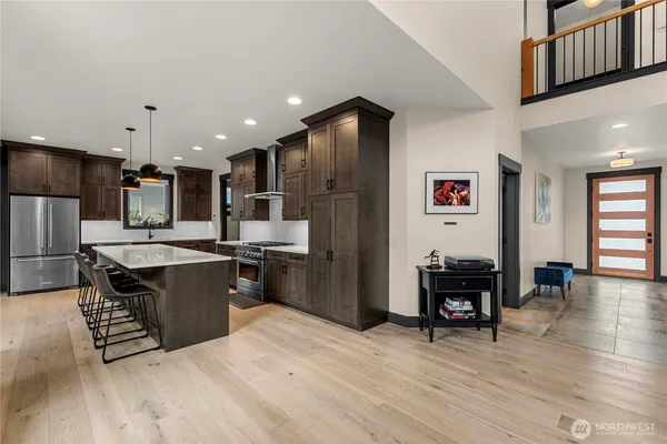 a kitchen with stainless steel appliances kitchen island granite countertop a refrigerator a stove a sink and a dining table with wooden floor