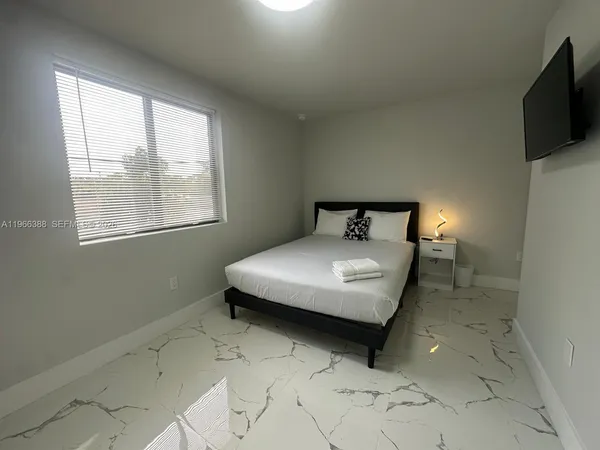 a bedroom with a bed and a flat tv screen on the dresser