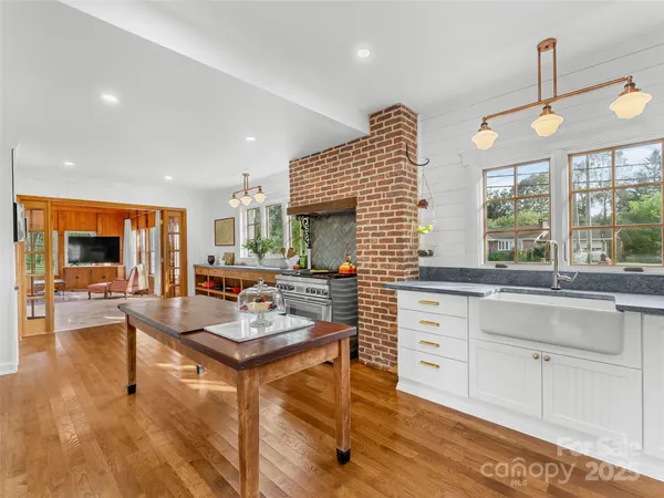 a kitchen with stainless steel appliances wooden floor and a sink