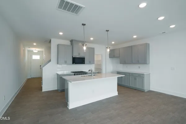 a large kitchen with a large counter top a sink stainless steel appliances and cabinets