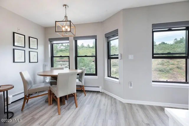 a dining room with wooden floor a chandelier a glass table and windows