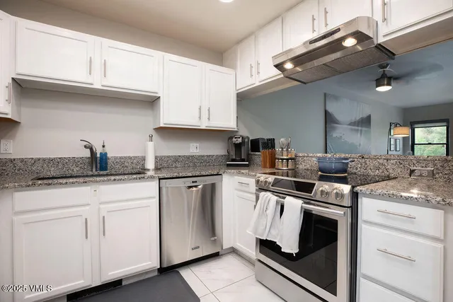 a kitchen with granite countertop white cabinets and appliances