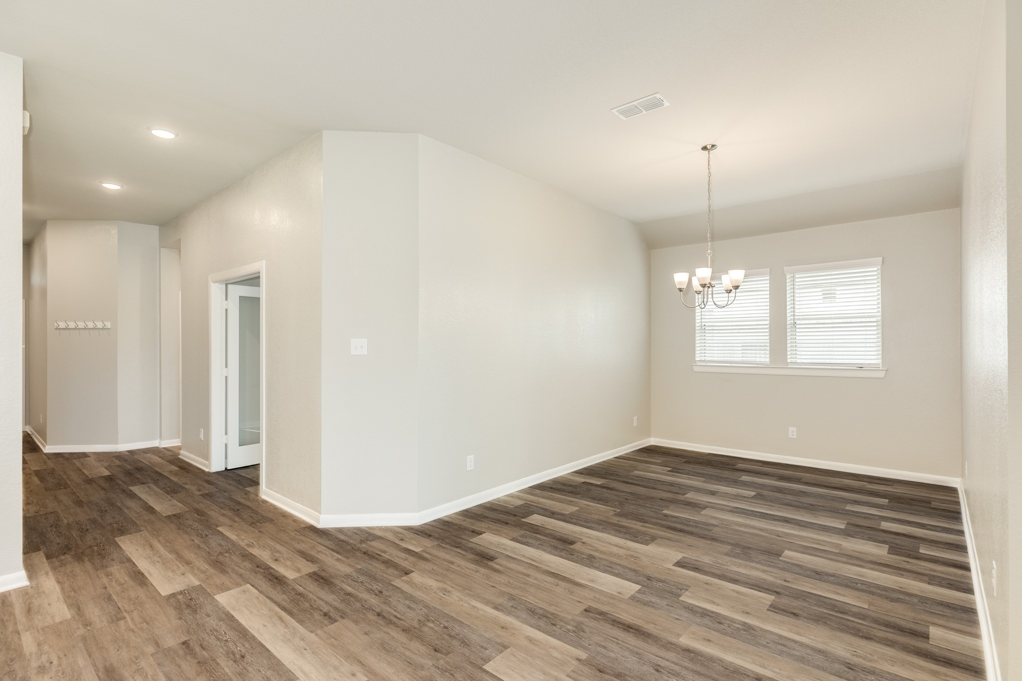 4946 Hitchings Court Rosharon, TX 77583 - Photo 11 of 49 Continuing down the hall, the entrance adjacent to the office leads to the dining area. It features large windows for abundant natural light, complemented by beautiful wooden floors and a modern chandelier.