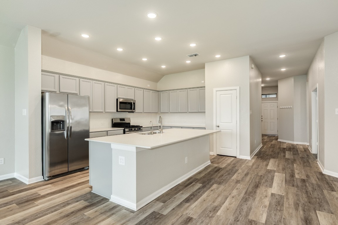 4946 Hitchings Court Rosharon, TX 77583 - Photo 12 of 49 The kitchen features an open layout with ample cabinet space, an oversized island with a granite countertop, a pantry, and stainless steel appliances.
