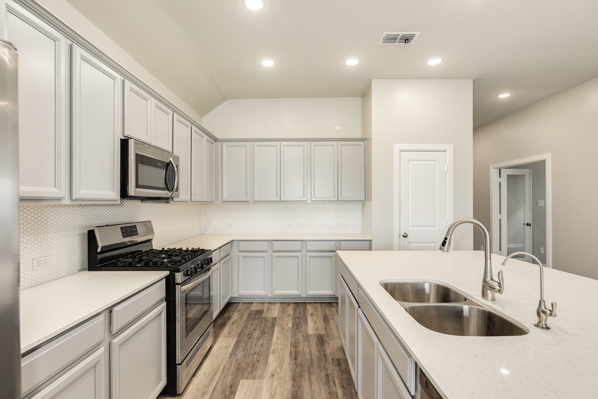 4946 Hitchings Court Rosharon, TX 77583 - Photo 13 of 49 Close-up of the kitchen showcasing ample cabinet storage, a 5-burner freestanding range, a microwave, and a pantry. The double doors to the office are visible in the background.