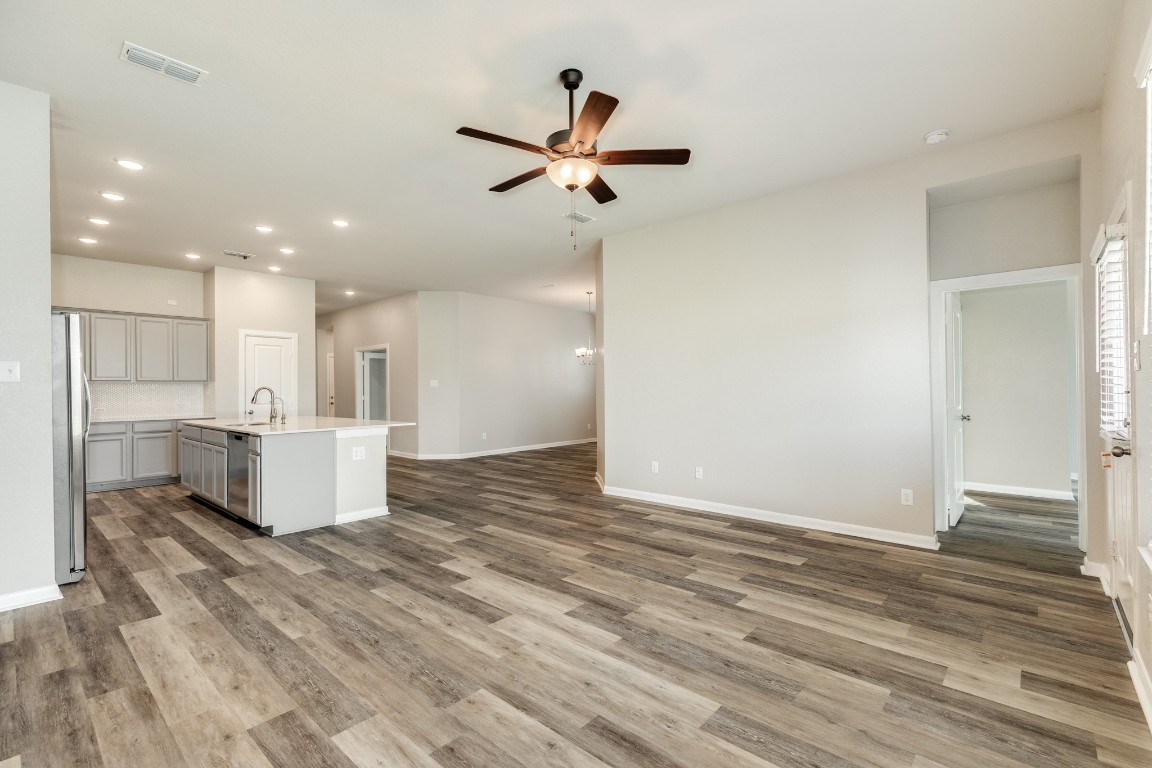 4946 Hitchings Court Rosharon, TX 77583 - Photo 15 of 49 This view highlights the open concept, showcasing the effortless transition from the dining area, through the kitchen, and into the family room. The door on the right provides access to the primary bedroom.