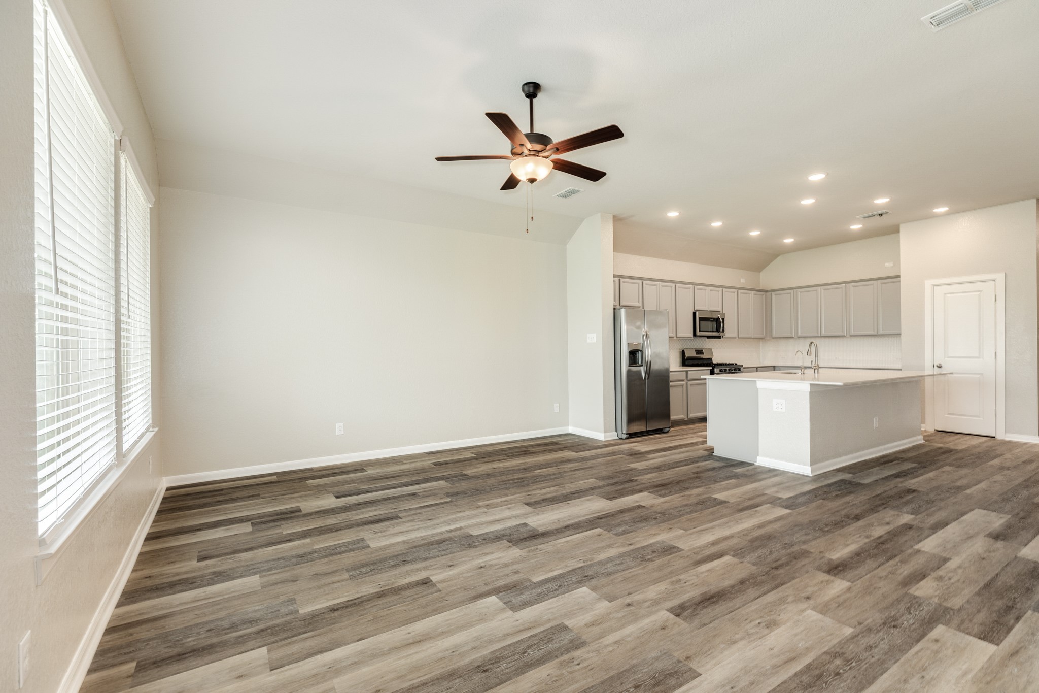 4946 Hitchings Court Rosharon, TX 77583 - Photo 48 of 49 This view showcases the seamless transition between the kitchen and family room, highlighting the open floor plan perfect for entertaining. The space features modern recessed lighting and a stylish ceiling fan.