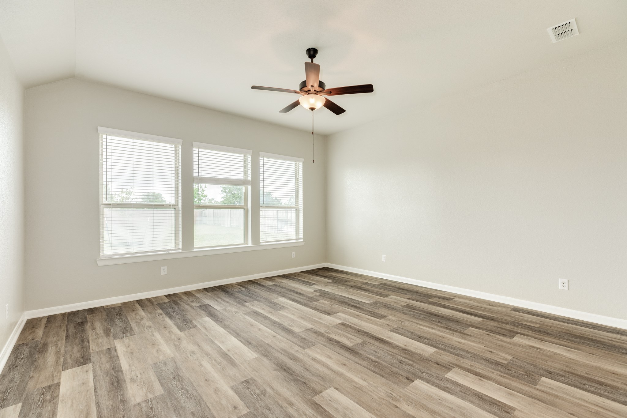 4946 Hitchings Court Rosharon, TX 77583 - Photo 19 of 49 Primary bedroom located off the family area has triple windows that overlook the backyard. The engineered wooden flooring continues throughout the home. The primary bathroom features a large walk-in shower.