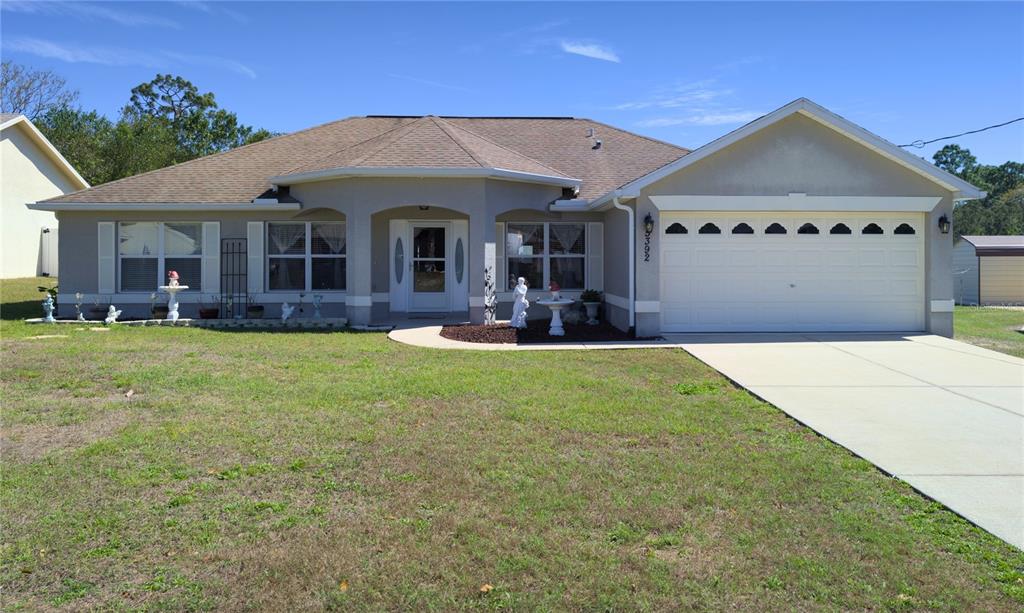 5392 Birchwood Road Spring Hill, FL 34608 - Photo 1 of 1 a front view of a house with a garden and yard