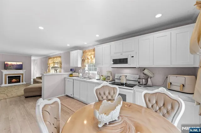 a kitchen with stainless steel appliances granite countertop a sink a stove a refrigerator cabinets and chairs