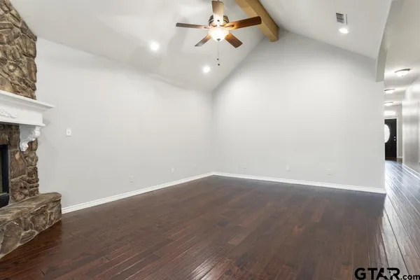 a view of an empty room with wooden floor and a fireplace