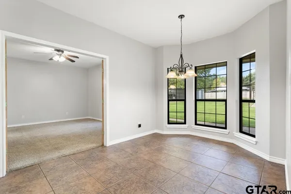 a view of an empty room with window and chandelier