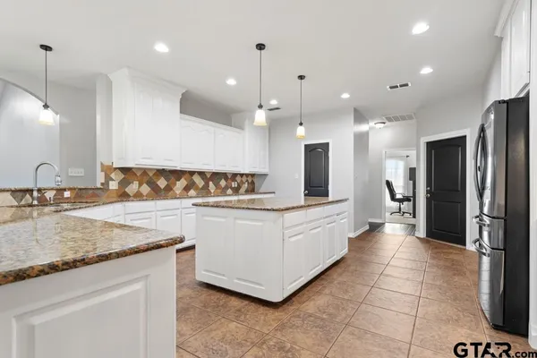 a large white kitchen with a refrigerator a sink and a counter top space