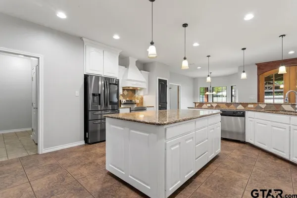 a kitchen with kitchen island a refrigerator stove a sink and a oven