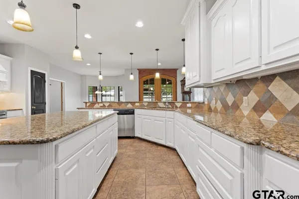 a large white kitchen with kitchen island a sink stainless steel appliances and cabinets