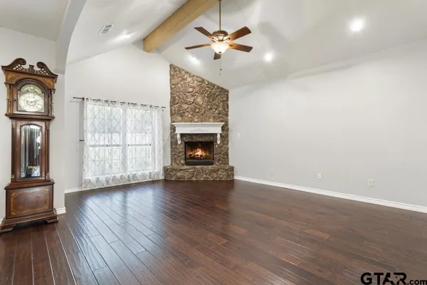 an empty room with windows fireplace and a chandelier fan