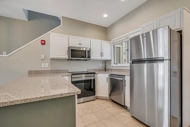 a open kitchen with granite countertop a stove top oven a sink dishwasher and a fireplace with wooden floor