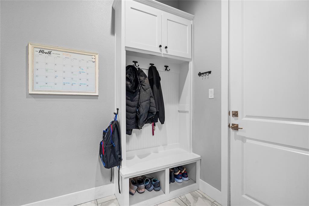 1024 Henry Way Springtown, TX 76082 - Photo 23 of 29 Built-in white mudroom cabinetry featuring upper storage, coat hooks, a bench, and lower shoe cubbies