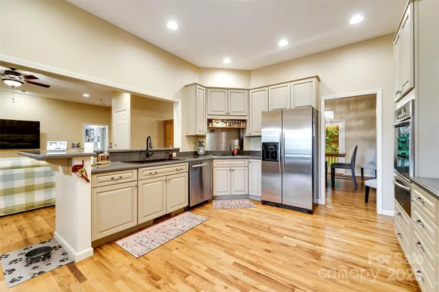 a large kitchen with stainless steel appliances kitchen island granite countertop a refrigerator and cabinets