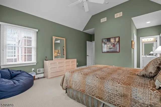 a bedroom with a bed couch and two windows