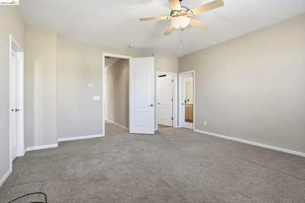 an empty room with chandelier fan and windows