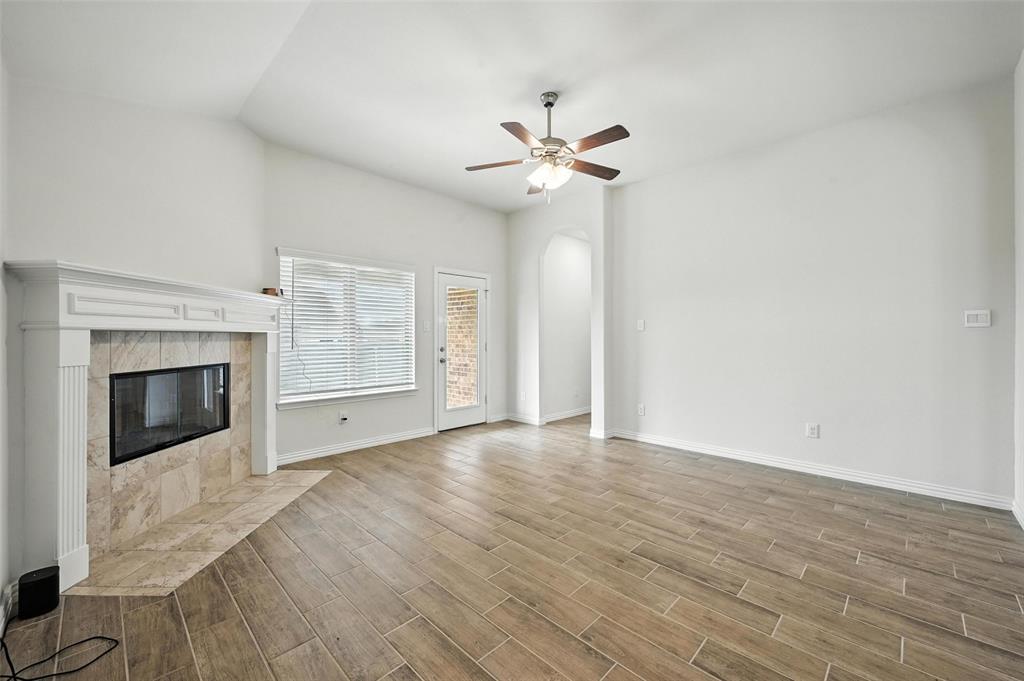 5 Pheasant Run Sanger, TX 76266 - Photo 17 of 27 Unfurnished living room featuring a tiled fireplace, arched walkways, wood tiled floors, and ceiling fan