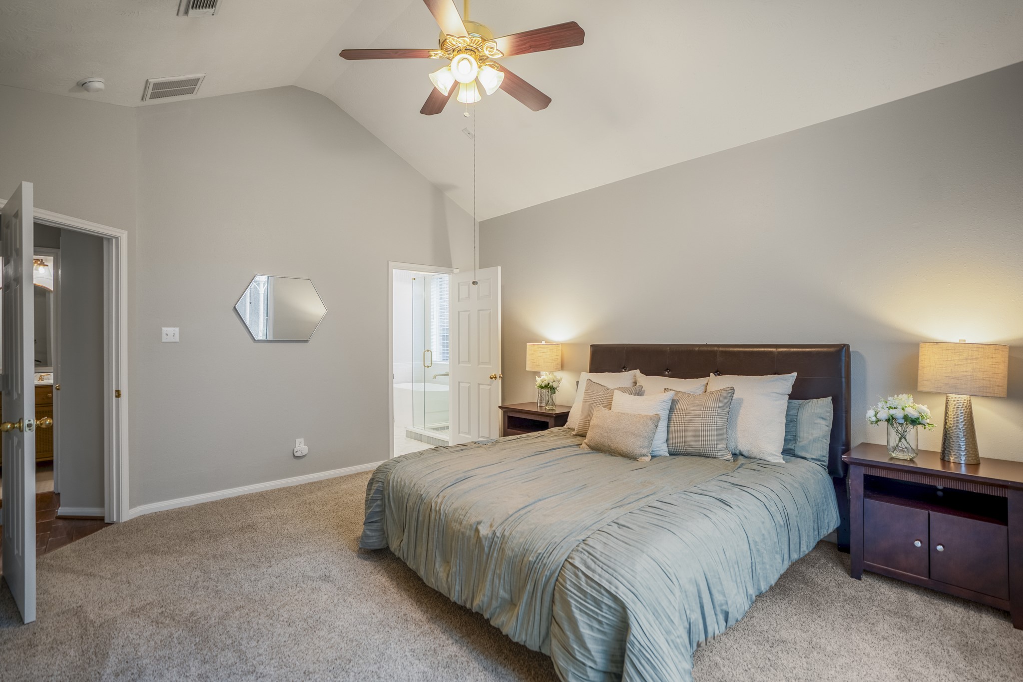 6311 Sparrows Glen Lane Spring, TX 77379 - Photo 18 of 50 Another look inside the primary bedroom highlights the calm neutral palette, soft carpet underfoot, and direct connection to the renovated bath just beyond the open doorway for an easy start to the morning.