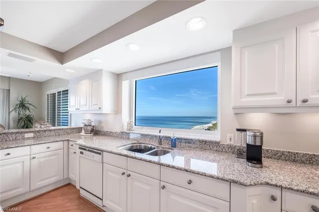 a kitchen with granite countertop white cabinets sink and stainless steel appliances