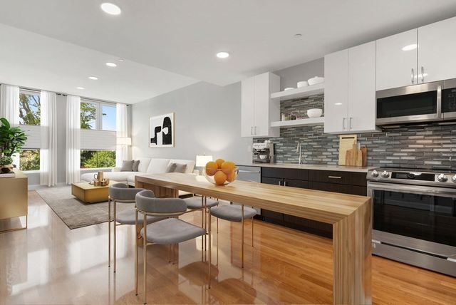 a kitchen with stainless steel appliances kitchen island granite countertop a stove a sink a microwave dining table and chairs