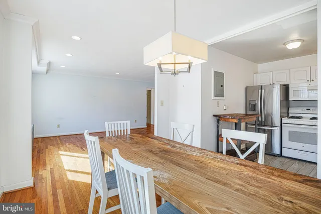 a kitchen with stainless steel appliances a dining table chairs and wooden floor
