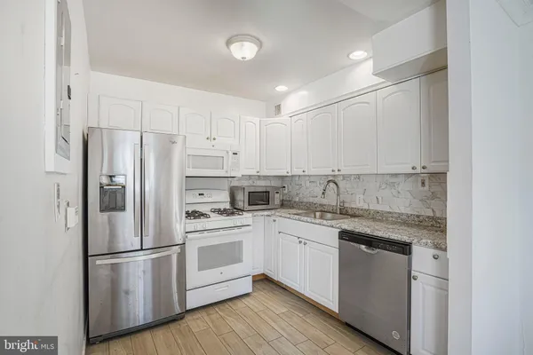 a kitchen with stainless steel appliances granite countertop white cabinets sink and white stainless steel appliances