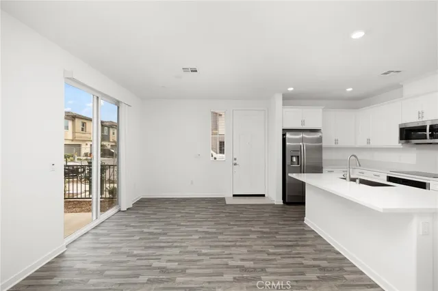 a room with stainless steel appliances a refrigerator a sink dishwasher and a stove with wooden floor