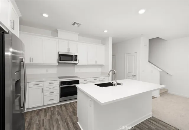 a kitchen with a sink a counter top space stainless steel appliances and cabinets