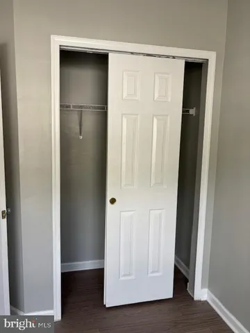 a view of an empty room with wooden floor & closet