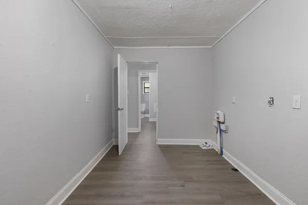 a large white kitchen with granite countertop a stove top oven a sink dishwasher and white cabinets with wooden floor